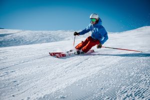 a man in a blue jacket skiing down a snow covered hill
